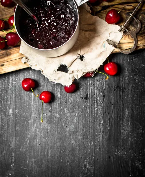 Fresh cherry jam in a saucepan on old Board. — Stock Photo, Image