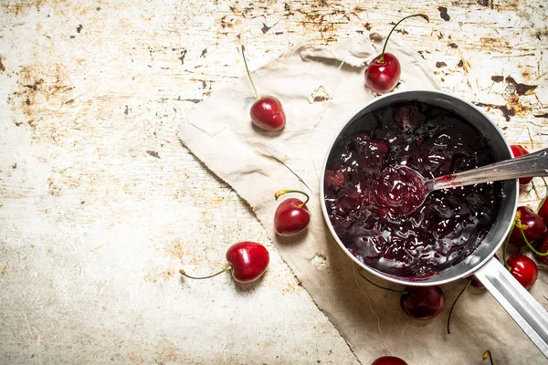 Confiture de cerises dans une casserole sur le vieux tissu . — Photo