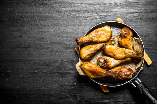 Bir tavada kızarmış tavuk budu.