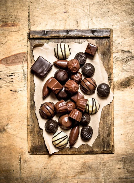 Different chocolates on old paper. — Stock Photo, Image