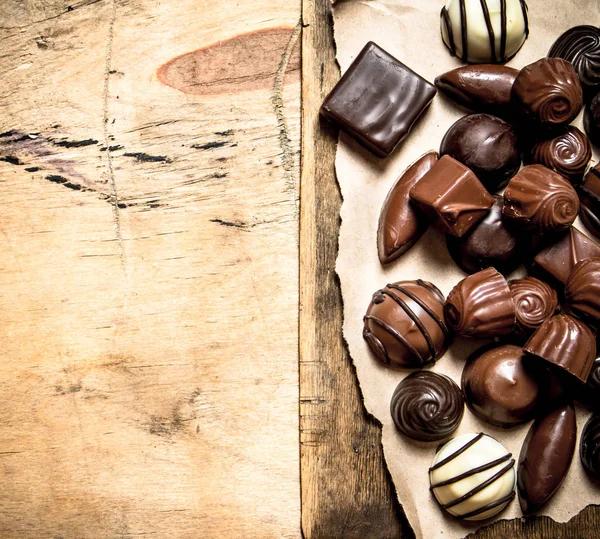 Different chocolates on old paper. — Stock Photo, Image