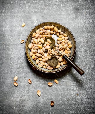 Bir kepçe ile eski bir tavada Antep fıstığı.