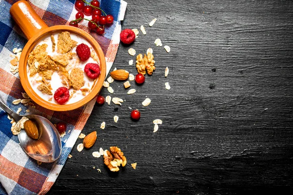 Muesli with berries, nuts and milk in the bowl.