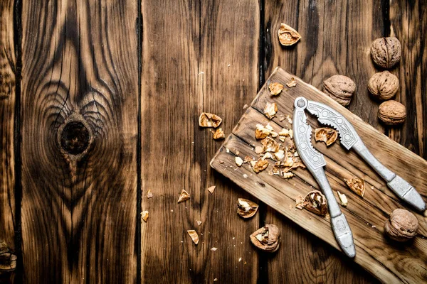 Walnüsse mit Nussknacker auf dem Brett. — Stockfoto