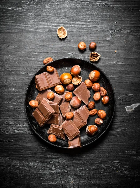 Schokoladenstücke mit Nüssen auf dem alten Teller. — Stockfoto