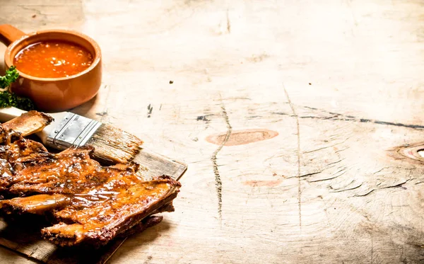 Smoked pork ribs with hot sauce and a brush. — Stock Photo, Image