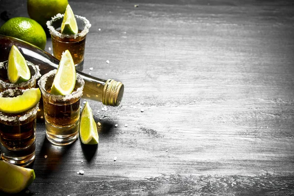 Bottle of tequila with shot glasses, fresh lime and salt. — Stock Photo, Image