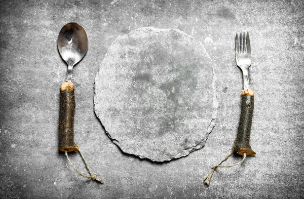 Piatto vuoto in pietra con cucchiaio e forchetta . — Foto Stock