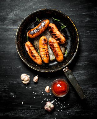 Tavada sarımsak ve domates soslu Kızarmış sosis.