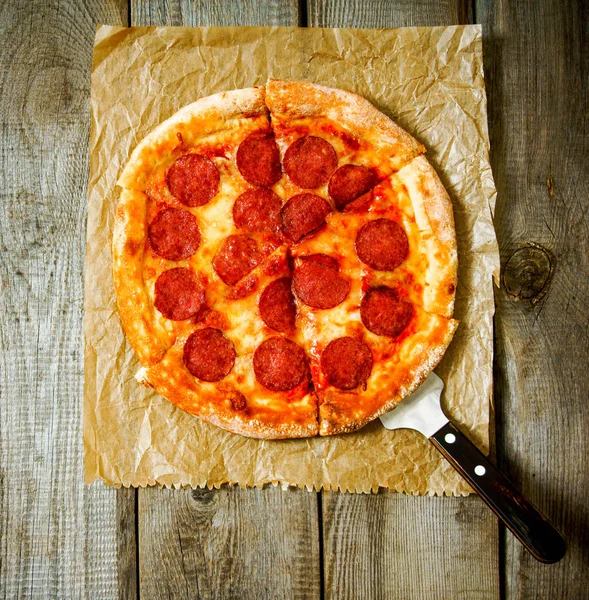 Sabroso pepperoni pizza en un papel viejo . — Foto de Stock