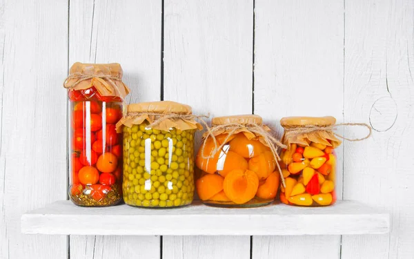 Preserved food in glass jars, on a wooden shelf — Stock Photo, Image