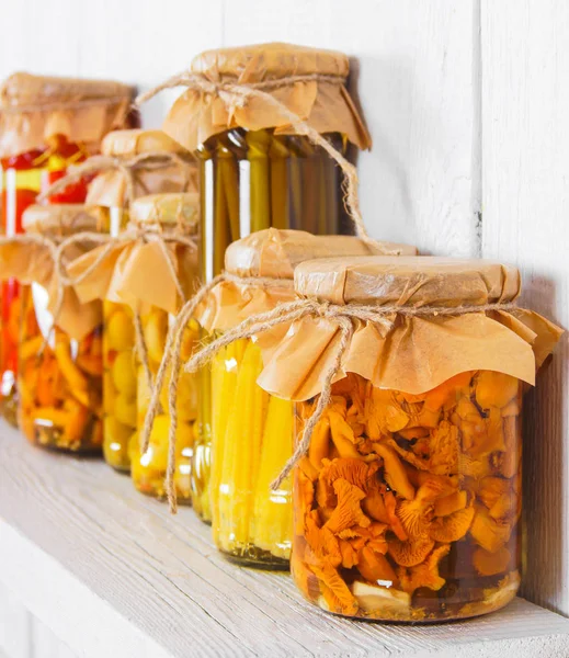 Preserved food in glass jars, on a wooden shelf — Stock Photo, Image