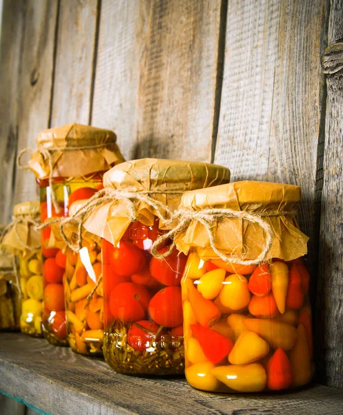 Preserved food in glass jars, on a wooden shelf. — Stock Photo, Image