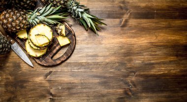 Bir bıçak ile kesme tahtası üzerinde ananas dilimlenmiş.