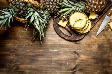 Bir bıçak ile kesme tahtası üzerinde ananas dilimlenmiş.