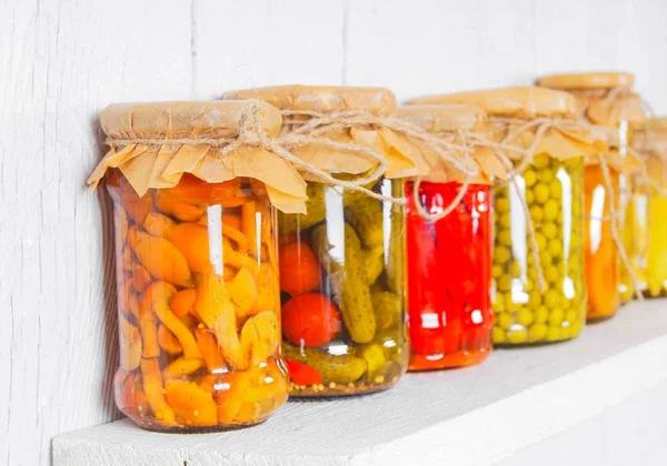 Preserved food in glass jars, on a wooden shelf — Stock Photo, Image