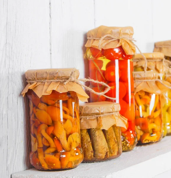 Preserved food in glass jars, on a wooden shelf — Stock Photo, Image