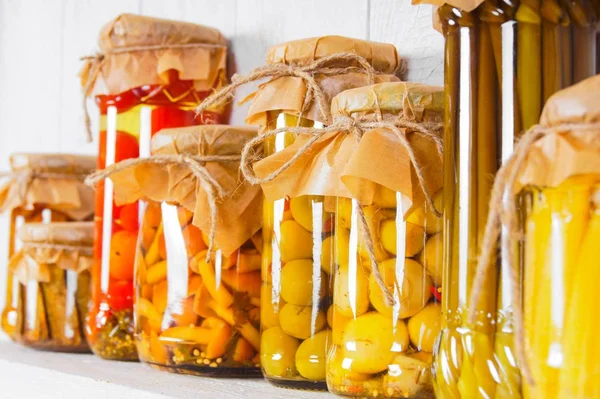 Preserved food in glass jars, on a wooden shelf — Stock Photo, Image