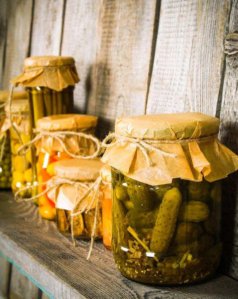 Preserved food in glass jars, on a wooden shelf. — Stock Photo, Image