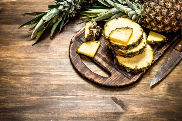 Piña en rodajas en una tabla de cortar con un cuchillo . — Foto de Stock