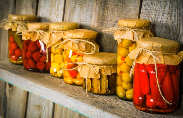 Preserved food in glass jars, on a wooden shelf. Stock Image