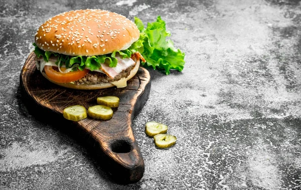 Fresh burger with vegetables and greens on an old board. — Stock Photo, Image