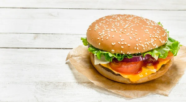 Hamburguesa con carne de res, queso y verduras sobre papel . —  Fotos de Stock