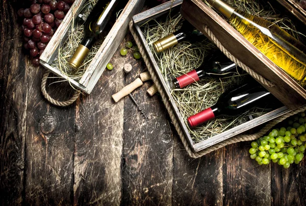 Fondo del vino. Botellas de vino tinto y blanco en cajas viejas . — Foto de Stock