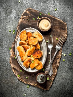 Tahta üzerinde peynir soslu tavuk nuggets.