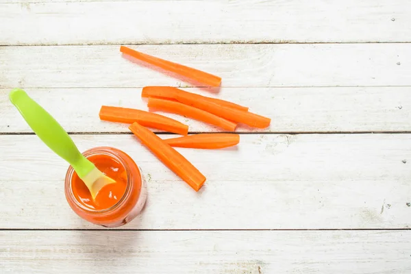 Comida para bebés. Puré de bebé de zanahorias frescas con una cuchara . — Foto de Stock