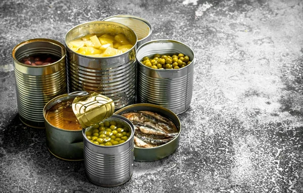 Various canned foods with meat, fish, vegetables and fruits in tin cans.