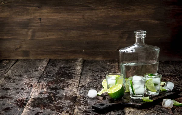 Vodka shots with lime and ice on the board. — Stock Photo, Image