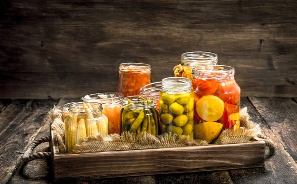 Legumes conservados diferentes de legumes e cogumelos em jarros de vidro . — Fotografia de Stock