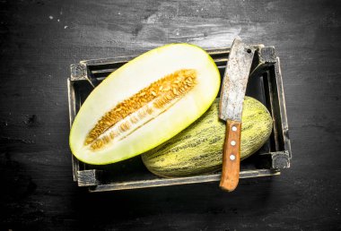 Bir balta ile bir kutu içinde taze kavun.