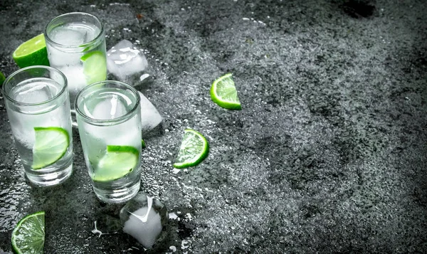 Vodka with pieces of lime and ice cubes. — Stock Photo, Image