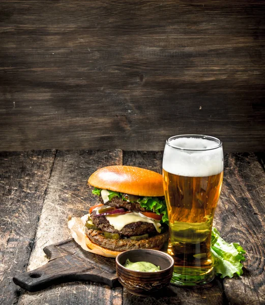 Comida rápida. Una hamburguesa grande con carne y un vaso de cerveza . —  Fotos de Stock