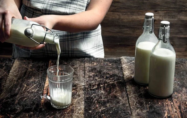 Donna versa latte di mucca fresco in un bicchiere . — Foto Stock