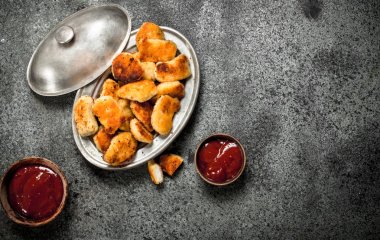 Tavuk nuggets bir kasede sos ile.