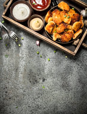 Tavuk nuggets eski bir tepsi üzerinde farklı sos ile.
