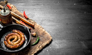 Bir tavada sarımsak ve baharat ile sosis.