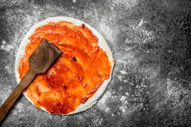 Pizza hazırlık. Domates sosu rulo hamur üzerinde uygulanması.