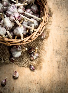 Eski bir sepet içinde sarımsak. Ahşap arka plan üzerinde.