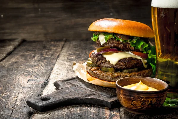 Comida rápida. Una hamburguesa grande con carne y un vaso de cerveza . —  Fotos de Stock