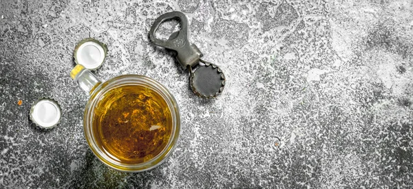 Glass of beer with a bottle opener and stoppers. — Stock Photo, Image