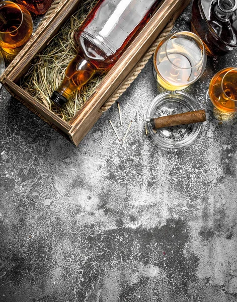 Cognac background. A bottle of cognac with lemon wedges and a cigar. — Stock Photo, Image