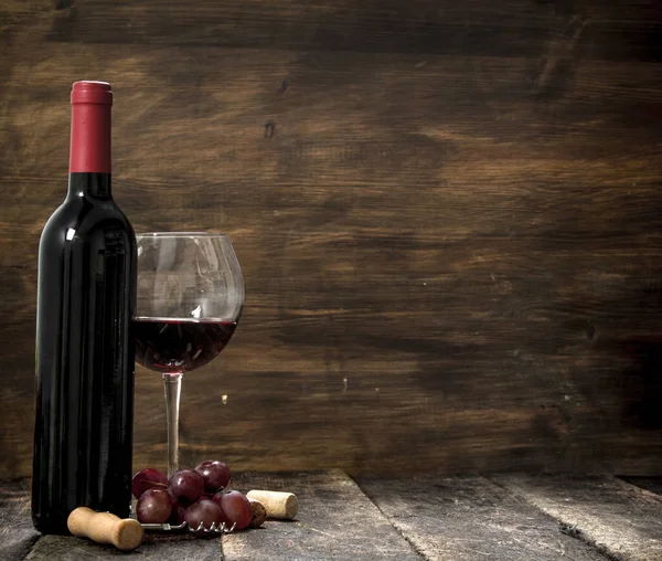 Red wine with a branch of grapes and a corkscrew. Stock Picture