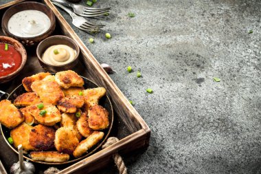 Tavuk nuggets eski bir tepsi üzerinde farklı sos ile.
