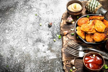 Farklı sos ile bir tavada tavuk nuggets.