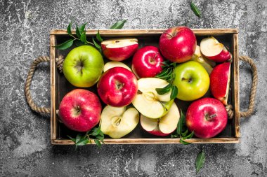 Bir ahşap tepsi içinde kırmızı ve yeşil elma.