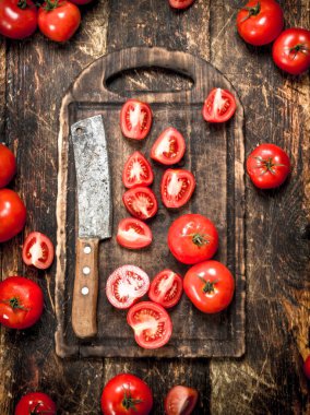 Bir kesme tahtası üzerinde eski balta ile taze domates.